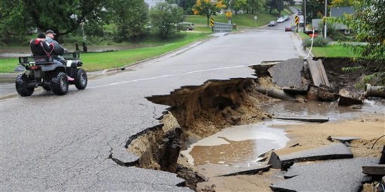 Mark Finner and his daughter, Kayla, drive past a damaged road along Oak Street in Arcadia, Wis. on Thursday, Sept. 23, 2010.  A state of emergency was declared for the Trempealeau County community after heavy rains flooded the area.  (AP Photo/Eau Claire Leader-Telegram, Dan Reiland)